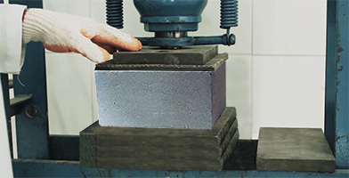 Um bloco de concreto sendo testando no quesito resistência à compressão 