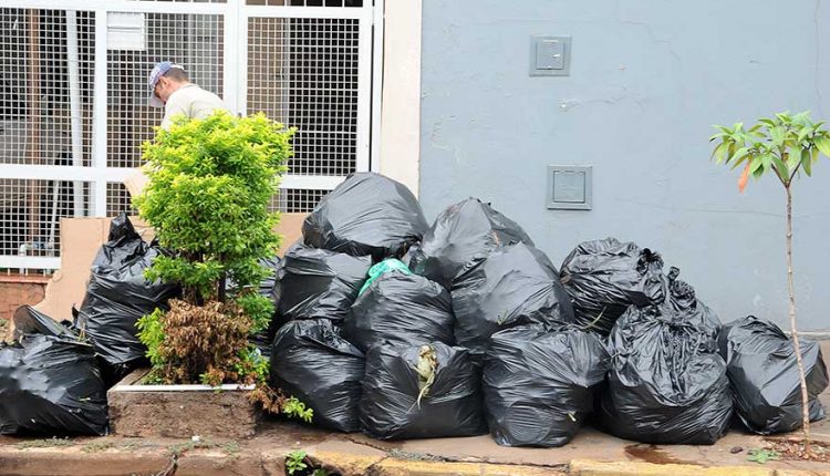 imagem de vários sacos de lixos cheios de resíduos na frente da portaria de uma casa