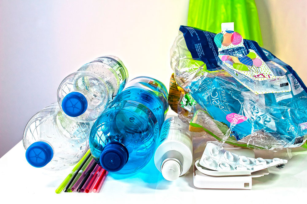 resíduos sólidos plásticos como garrafas, canudos, embalagens, caixas de remédios, lacres, caixas de shampoo em cima de uma mesa