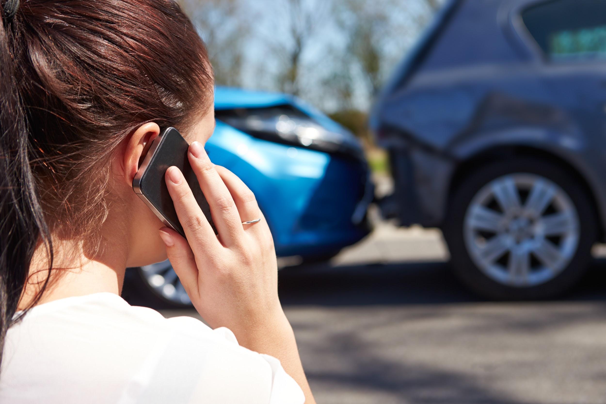 Qual é a diferença entre sinistro e recuperado: mulher falando ao celular enquanto dois carros aparecem colididos