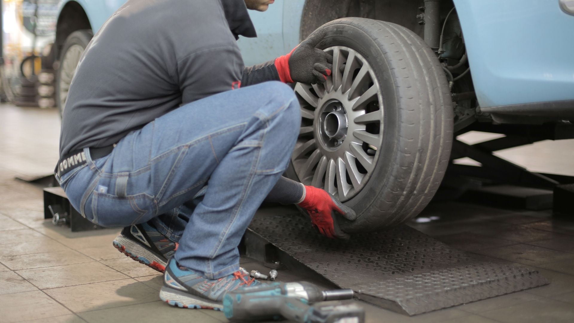 Mecânico fazendo a troca de um pneu careca, mostrando o motivo de fazer a manutenção do veículo.